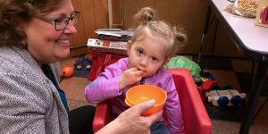 Therapist helps child feed herself