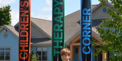 Child standing in front of crayon structure at Children's Therapy Corner in Midland